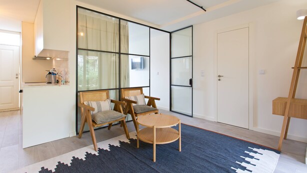 A modern living room with a sofa, chairs, a small table, and a large window with curtains. - VIVA Travessa dos Campos Serviced Apartments D (Porto)