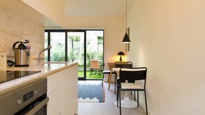 A modern kitchen with a built-in oven, a coffee machine, and a dining area with a table and chairs. - VIVA Travessa dos Campos Serviced Apartments D (Porto)
