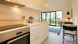 A modern kitchen with a built-in oven, a sink, and a window overlooking a garden. - VIVA Travessa dos Campos Serviced Apartments D (Porto)