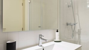 A modern bathroom with a white sink, a mirror, and a glass shower enclosure. - VIVA Travessa dos Campos Serviced Apartments D (Porto)