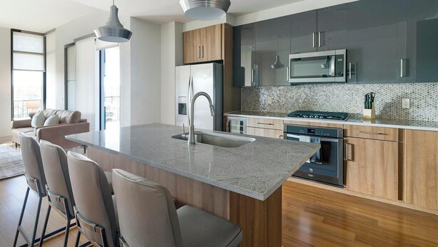 Una cocina moderna con una isla central, electrodomésticos de acero inoxidable y una zona de estar con taburetes de bar.