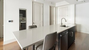 Een moderne keuken met een lange aanrecht, twee stoelen, een vaatwasser en een spoelbak.