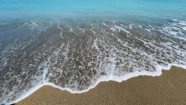 Una spiaggia con acque cristalline, un litorale sabbioso e un cielo sereno.