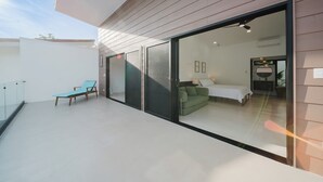 Un intérieur moderne avec une porte vitrée donnant sur une chambre, un canapé vert et un fauteuil bleu.