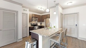 Eine moderne Küche mit Granit-Arbeitsplatten, Edelstahlgeräten und einer zentralen Kochinsel mit Sitzgelegenheiten.