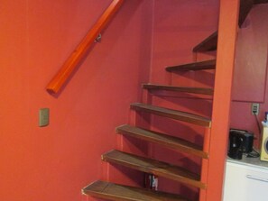 Una escalera con escalones de madera y una pared roja.