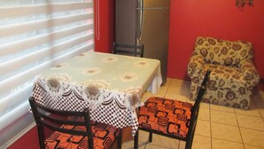 A compact kitchen with a refrigerator, a dining table with chairs, and a patterned sofa. - B5 Furnished cottage near downtown Puerto Montt (Puerto Montt)