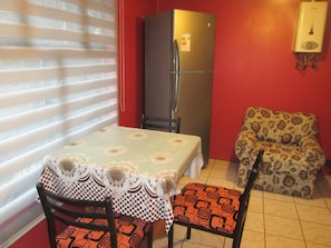 Una cocina compacta con un refrigerador, una mesa de comedor con sillas y un sofá estampado.