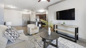 A modern living room with a sofa, a coffee table, and a TV mounted on the wall. - Landing | Beautiful 2BD, Clubhouse (Carrollton)