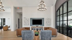 A modern lounge area with a large seating arrangement, a central coffee table, and a television mounted on the wall. - Landing | Chic 1BD, Pool, Gym (Athens)