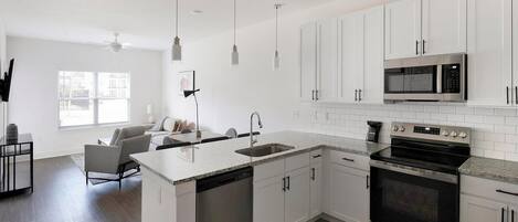 A modern kitchen with white cabinetry, a built-in microwave, and a stainless steel oven.
