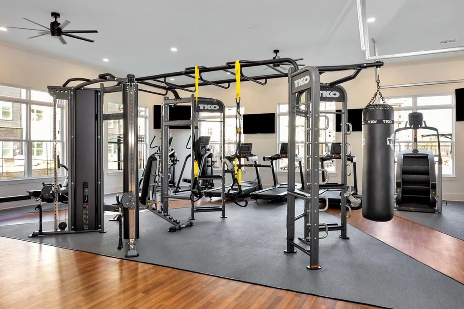 Une salle de sport équipée de divers appareils d’entraînement, notamment des appareils de musculation et des appareils de cardio, ainsi qu’un sac de frappe.