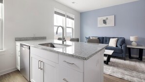 Una cocina moderna con encimera de granito, lavavajillas integrado y una ventana con persianas.