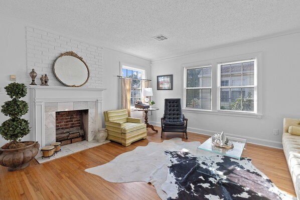A living room with a fireplace, a large mirror, a leather sofa, and a glass coffee table.