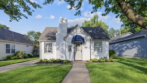 A two-story house with a front porch, a chimney, and a mailbox. - Adorable 2-bedroom cottage in midtown Tulsa with a dreamy weeping willow. (Tulsa)