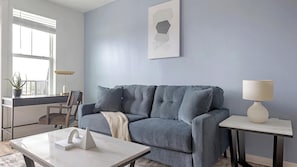 A living room with a grey sofa, a small table, a lamp, and a potted plant. - Landing | Incredible 1BD, Gym, Clubhouse (Rome)