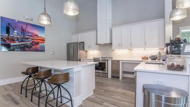 A modern kitchen with white cabinetry, a central island with bar stools, stainless steel appliances, and pendant lighting. - Landing | Spectacular 1BD, Gym, Clubhouse (Rockport)