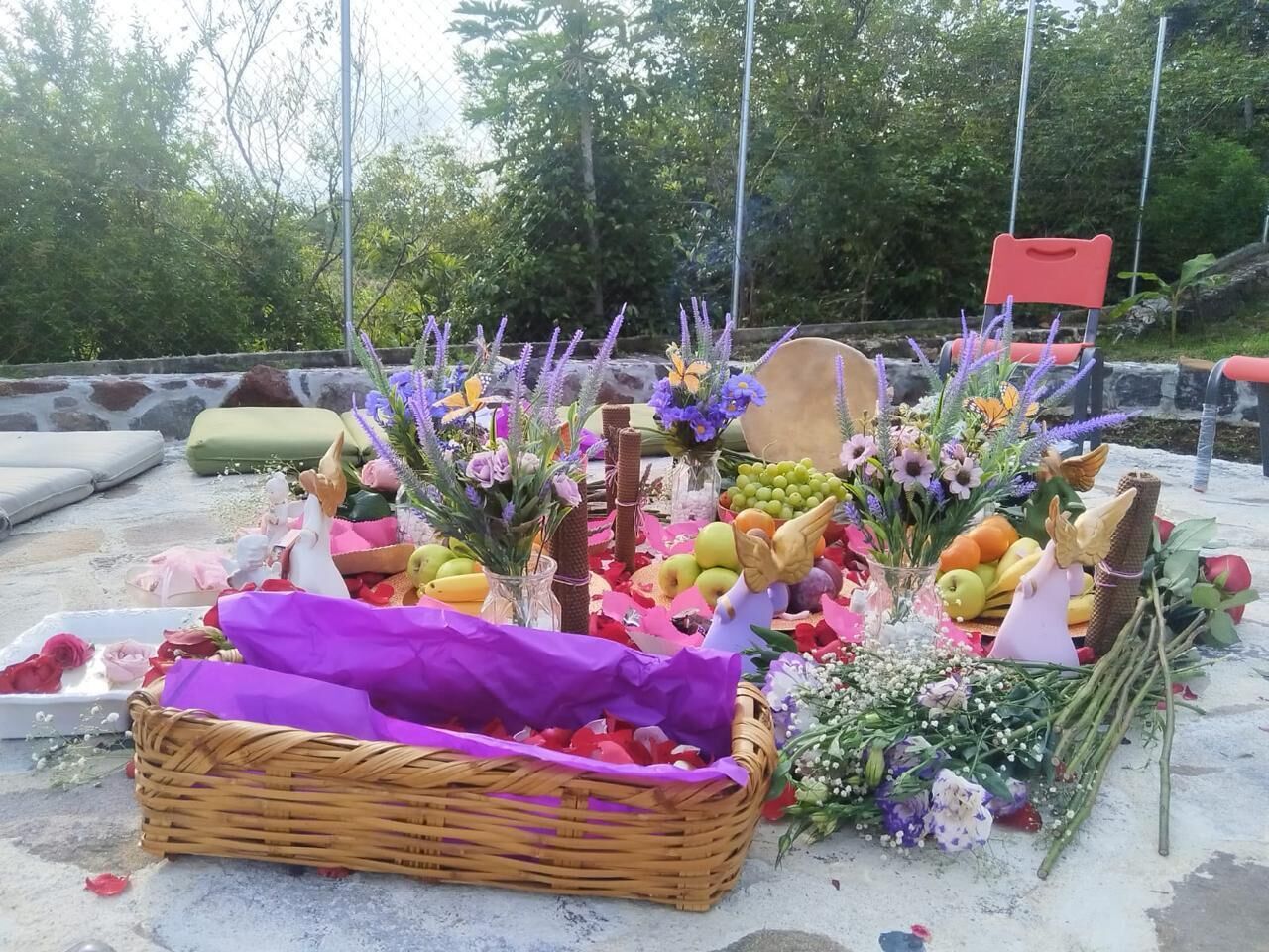 A display of fruits, flowers, and a wicker basket on a concrete surface.