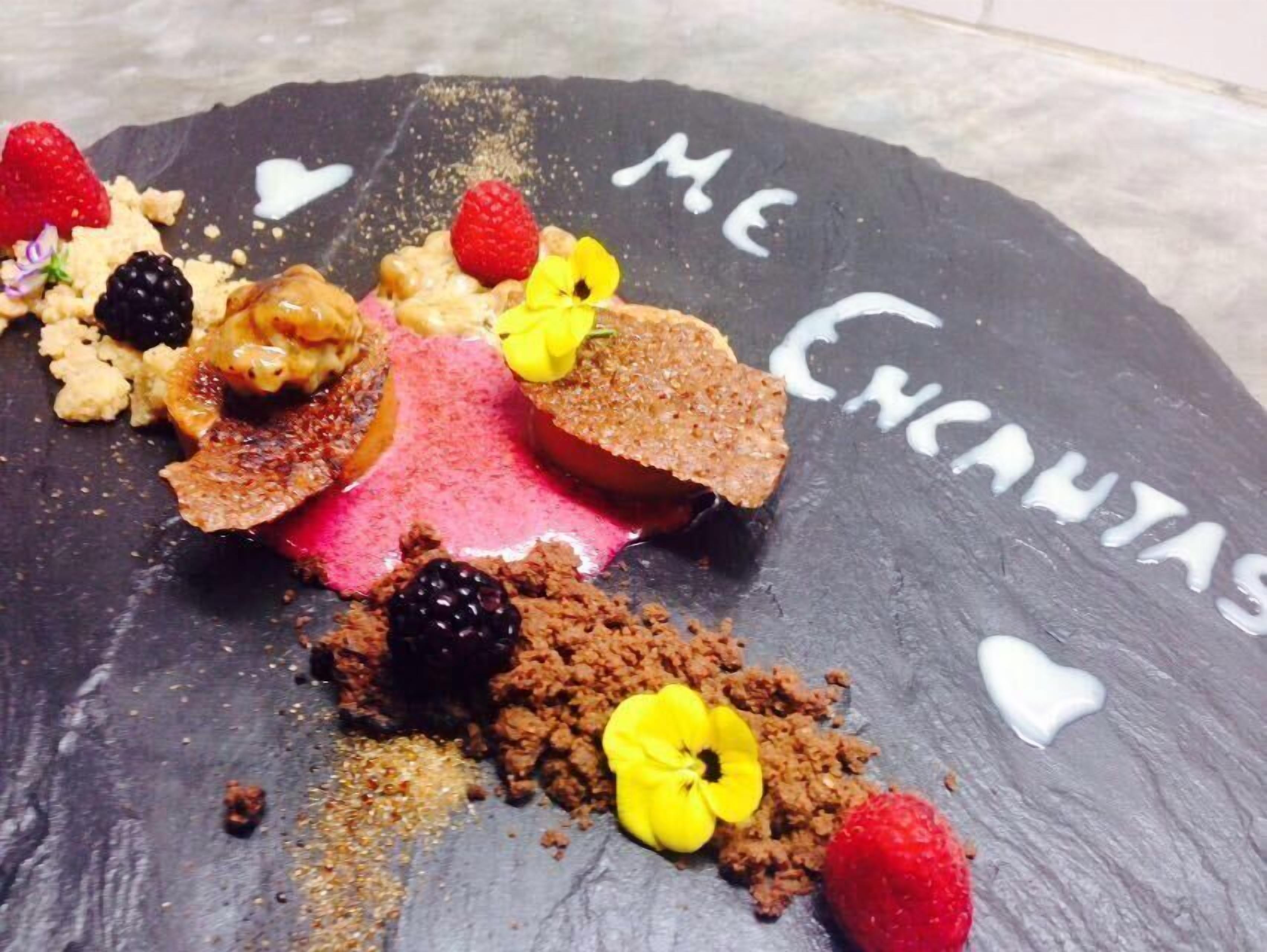 A dessert on a slate board with 'ME ENCHANTAS' written on it.