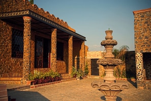A stone building with columns, a fountain, and a covered area with plants. - Wellness Petfrendly El Secreto (Tepoztlan)
