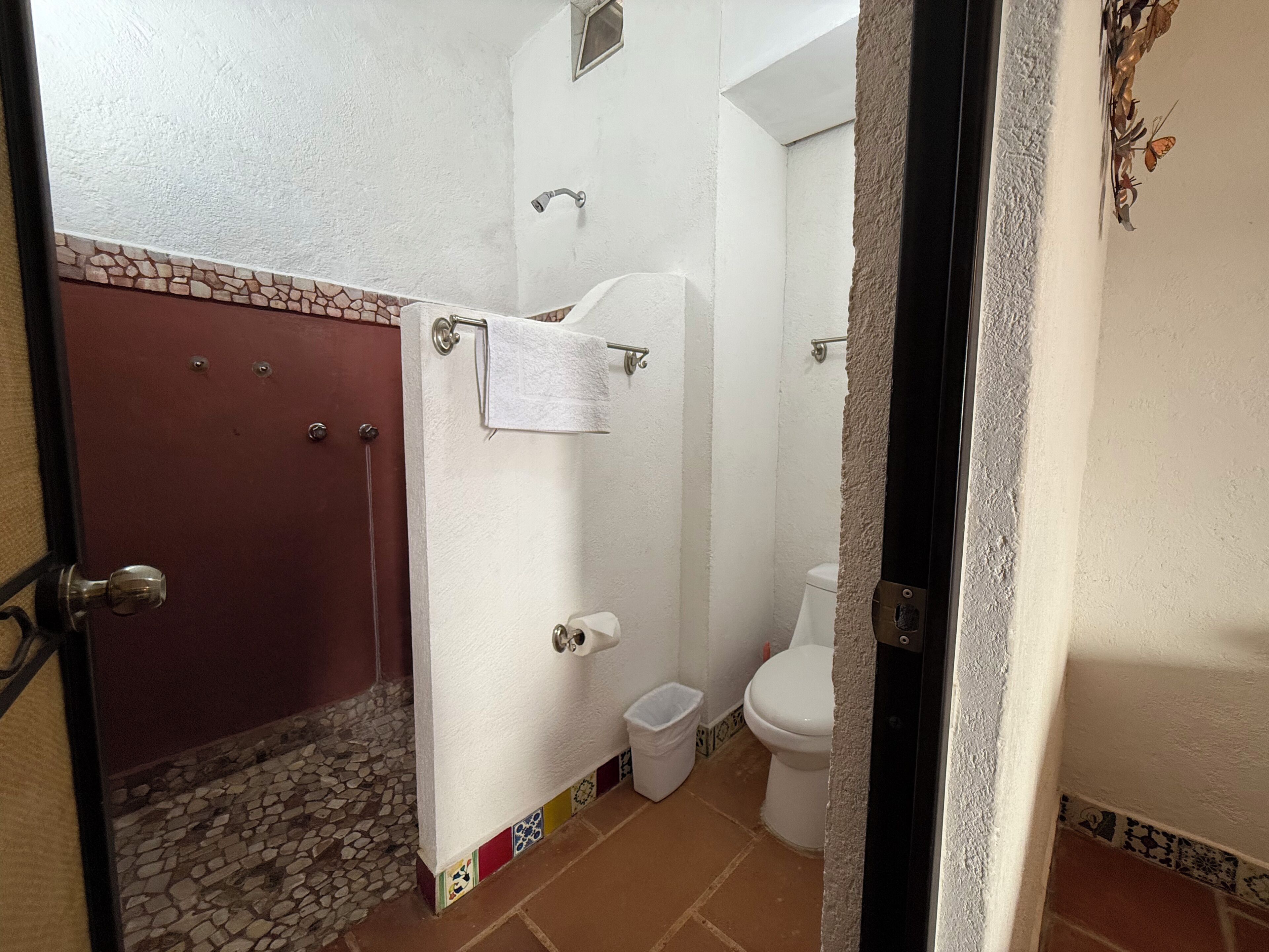 Ein Badezimmer mit Dusche, Toilette und einem Handtuch an der Wand.