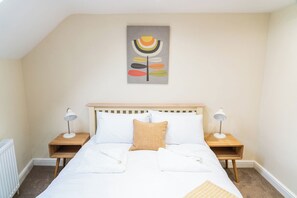 A bedroom with a bed, two bedside tables, a nightstand, a radiator, and a wall-mounted artwork. - Cosy Cottage in the heart of Pickering North Yorkshire (Pickering)