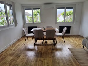 Ein Essbereich mit Holztisch und -stühlen, großen Fenstern und einer Heizung.