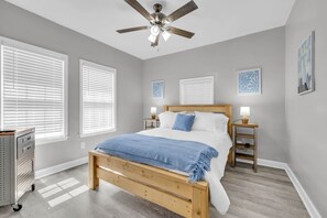 Ein Schlafzimmer mit einem hölzernen Bett, weißer Bettwäsche, einem Deckenventilator und zwei Nachttischen mit Lampen.