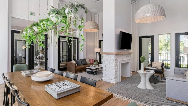 Un amplio espacio habitable con una mesa de comedor de madera, una chimenea y plantas colgantes.