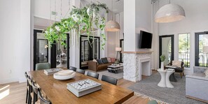 Un amplio espacio habitable con una mesa de comedor de madera, una chimenea y plantas colgantes.