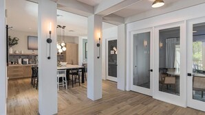 Una cocina amplia con piso de madera, un comedor con sillas y una puerta de vidrio que da a un espacio de estar exterior.