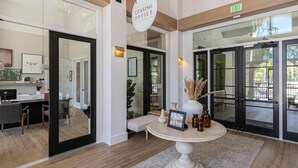 A modern interior with a desk, chairs, a round table with decorative items, and a large mirror. - Landing | Amazing 1BD, Clubhouse, Gym (Lakeland)