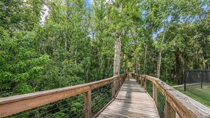 A wooden boardwalk through a forest with a metal fence on one side. - Landing | Amazing 1BD, Clubhouse, Gym (Lakeland)