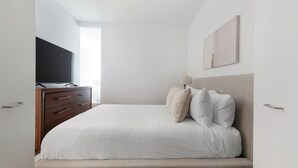 Ein Schlafzimmer mit Bett, Schminktisch, Fernseher und Fenster.