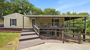 A two-story building with a covered deck and a fenced area. - Peaceful 3-bedroom house with AC in charming Kingston (Kingston)
