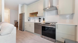 A modern kitchen with stainless steel appliances, white cabinetry, and a built-in oven.