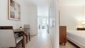 Ein Hotelzimmer mit einem Bett, einem Schreibtisch mit Stühlen, einem kleinen Tisch mit Pflanze und einem Schrank.
