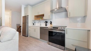 Una cocina moderna con electrodomésticos de acero inoxidable, armarios blancos y un horno integrado.
