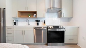 Eine moderne Küche mit Edelstahlgeräten, weißen Schränken und einem eingebauten Backofen.