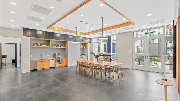 Una cocina moderna con armarios de madera, un comedor con mesa y sillas de madera, y un amplio ventanal con vistas al exterior.