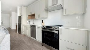 A modern kitchen with white cabinetry, stainless steel appliances, and a built-in oven.