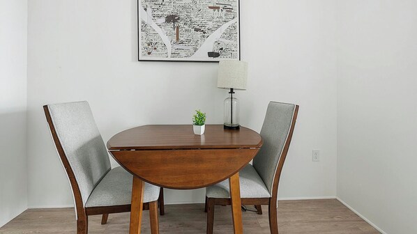 A dining table with two chairs, a small potted plant, and a lamp on the table.
