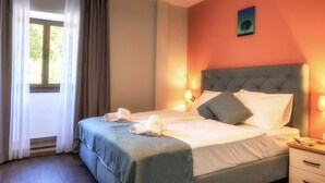 Ein ordentlich bezogenes Bett mit Kissen und einem gefalteten Handtuch, eine Nachttischlampe und ein Bild an der Wand.
