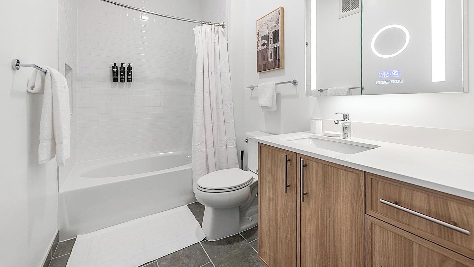 Une salle de bain moderne équipée d’une baignoire, de toilettes et d’un meuble-lavabo avec un miroir.