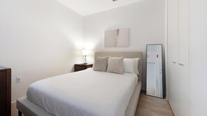 Ein Schlafzimmer mit einem Bett, einem Nachttisch, einer Lampe und einem Spiegel.