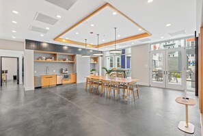 A modern kitchen with wooden cabinets, a dining area with a wooden table and chairs, and a large window providing a view of the outside. - Landing | Stunning 1BD, Pool, Gym (Hyattsville)