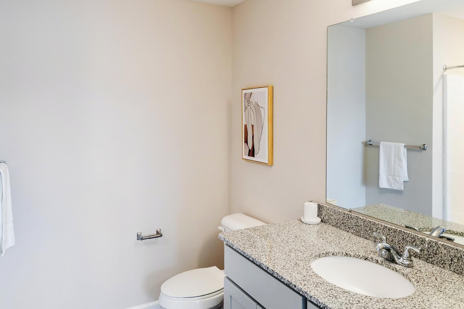 Une salle de bain équipée de toilettes, d’un lavabo, d’un miroir et d’un porte-serviettes.