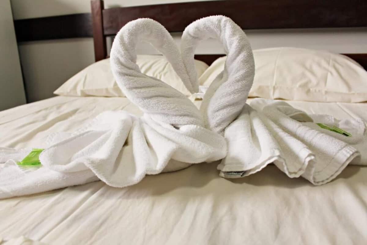 A bed with white linens and two towels shaped like swans.