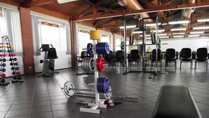 Uma academia com equipamentos de musculação, um banco e máquinas de exercício.