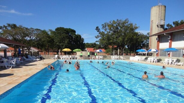 Piscina com água azul cristalina, rodeada por espreguiçadeiras e guarda-sóis.